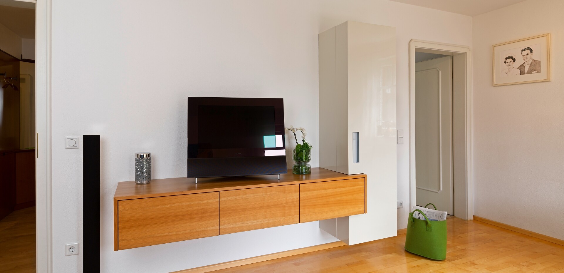 Wohnzimmer mit einer Anrichte in Kirschbaum und einem Barschrank in weißem Hochglanzlack.